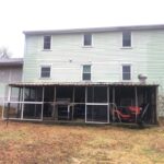 Before photo showing old metal screen house attached to back of home.